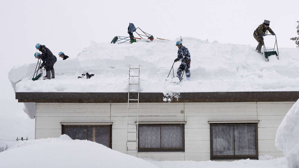 people clearing deep snow off the roof of a house in mid winter in Myoko Kogen Japan